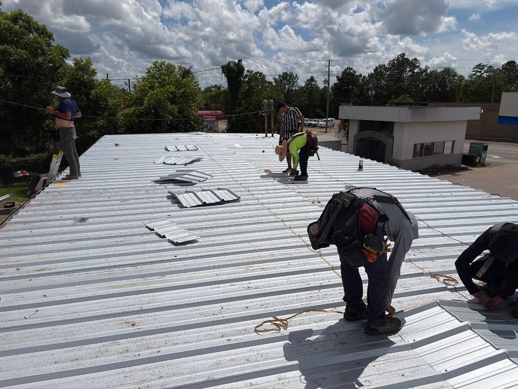 Crew installing corrugated metal roofing on a commercial building