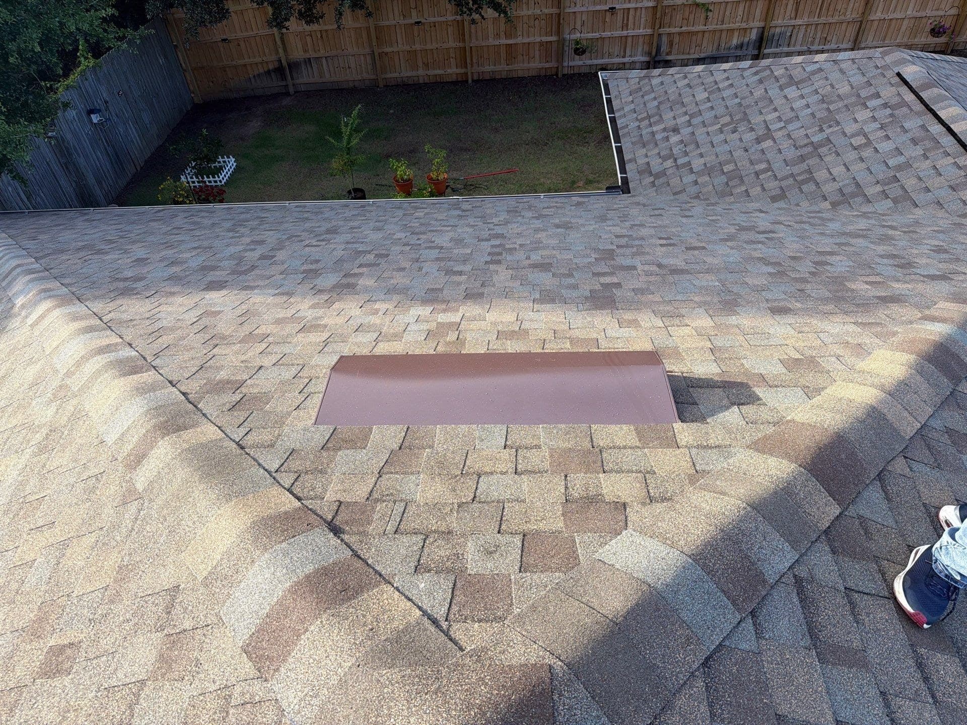 New skylight cover flashed into an architectural shingle roof, seen from the ridge
