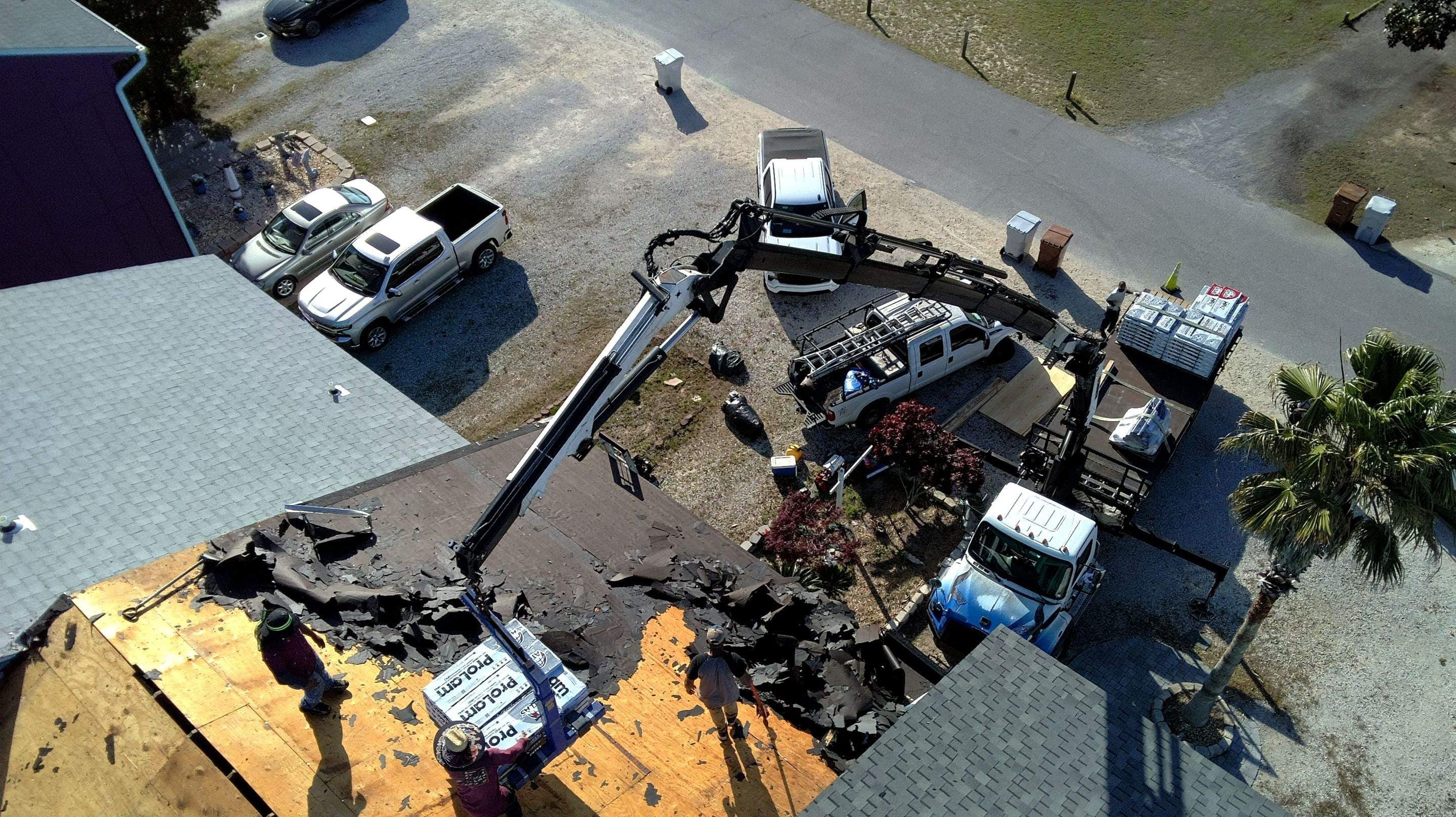 Crane removing tear-off debris with the roof deck exposed