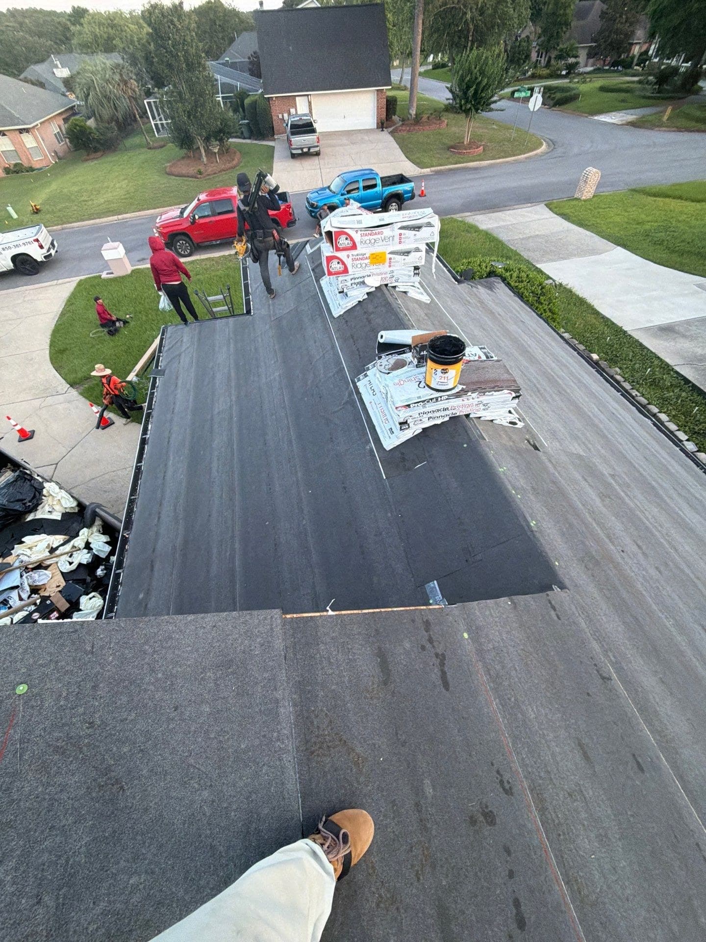 Roof dried in with underlayment, shingle bundles staged on the ridge